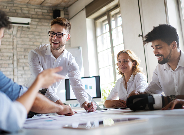 people smiling and working around table