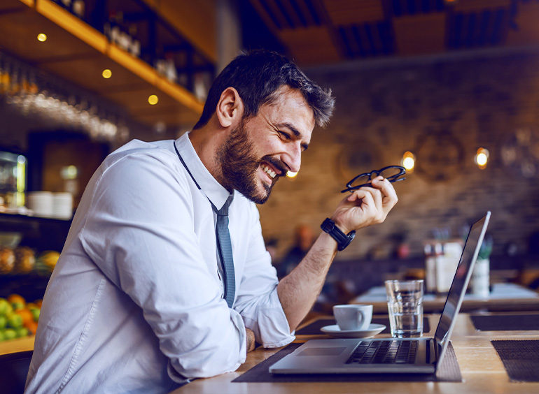 man on video chat on laptop at restaurant